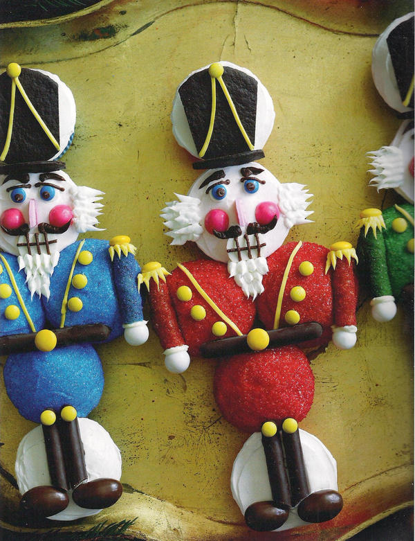 Decorative nutcracker-themed cupcakes with blue, red, and green icing, arranged on a light surface